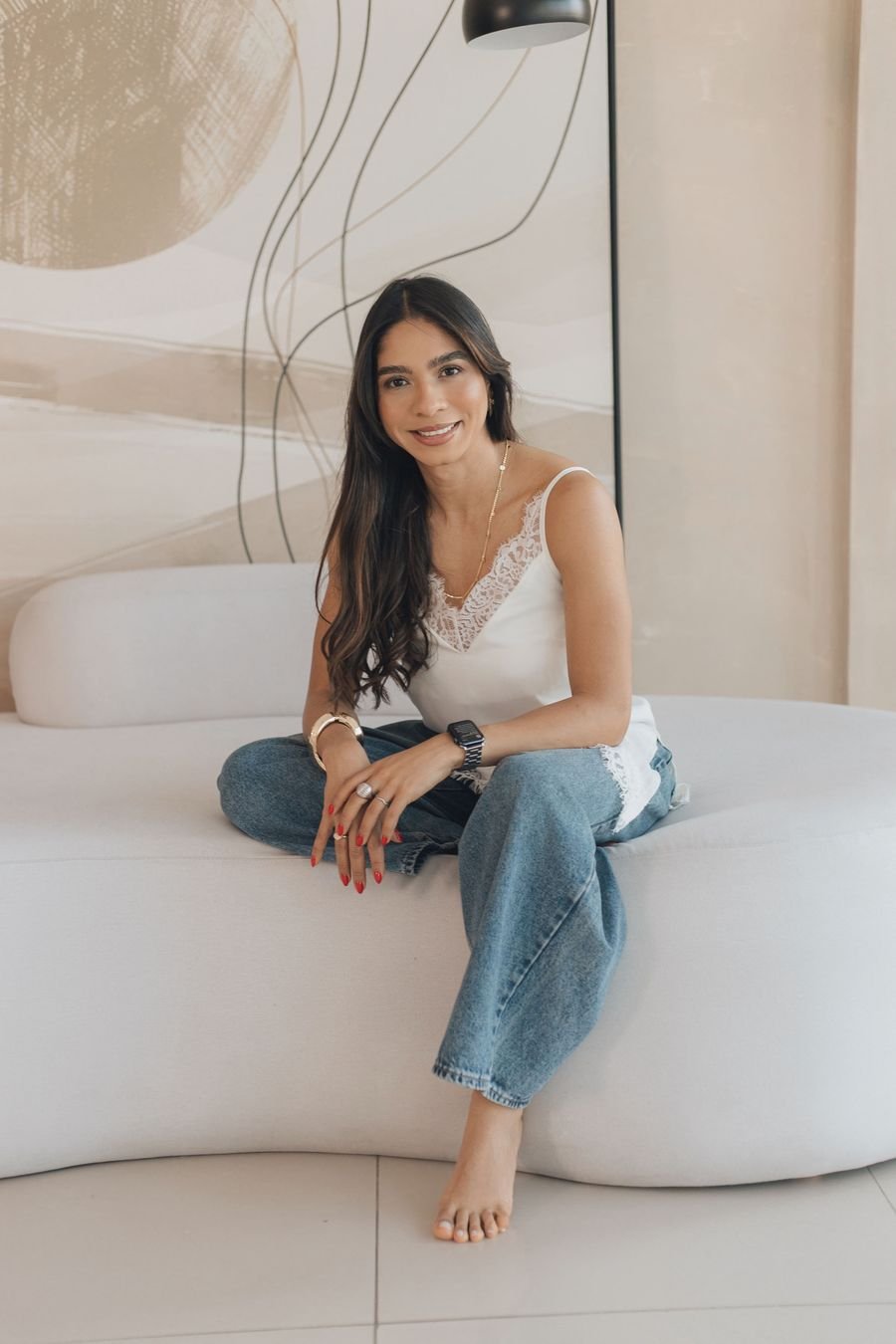 Vanessa Tavares sorrindo, sentada em um sofá claro